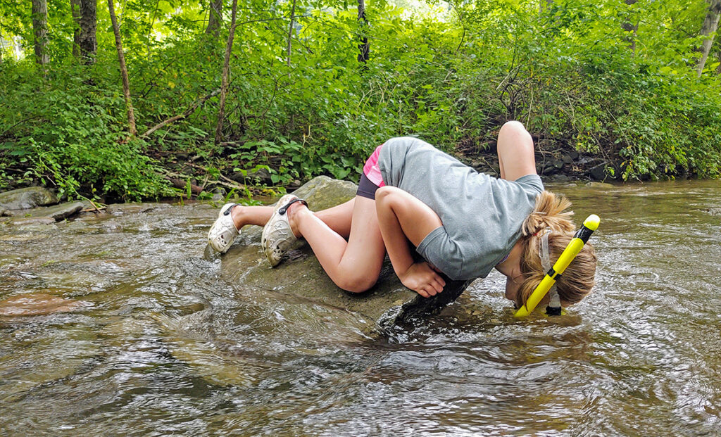 person with snorkling mask looking into the stream